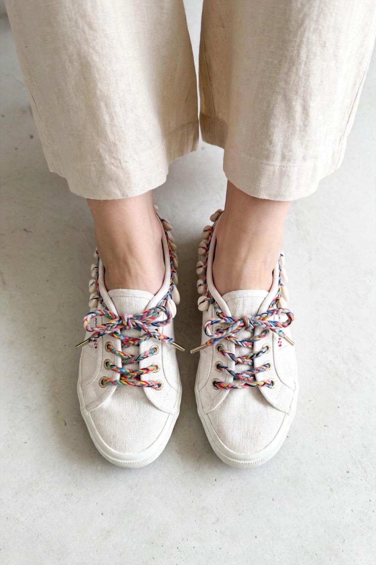 Baskets Superga x Alanui beige clair, lacets multicolores et coquillages cauris, portées — Seconde Main VestiaireFMR