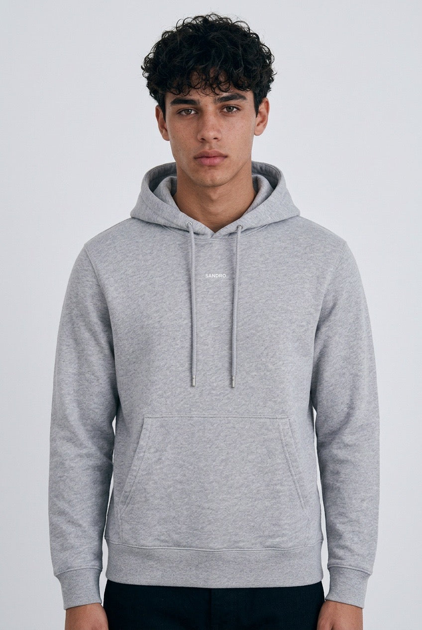 Jeune homme de face portant un sweat à capuche Sandro Homme – Seconde main luxe – VestiaireFMR Genève Suisse