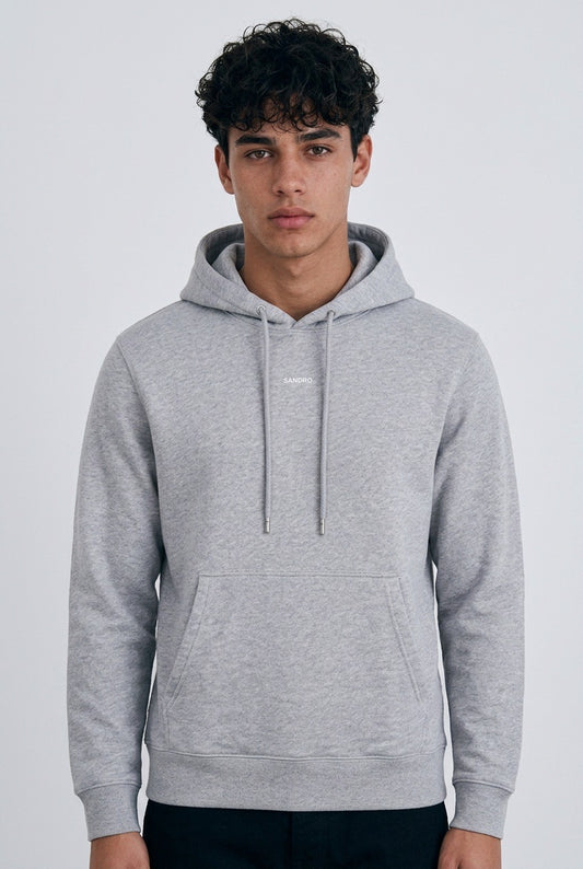 Jeune homme de face portant un sweat à capuche Sandro Homme – Seconde main luxe – VestiaireFMR Genève Suisse